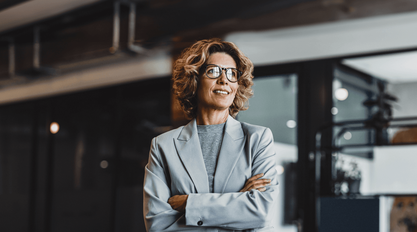 RegTech - foto de uma mulher em ambiente corporativo, de braços cruzados e sorrindo