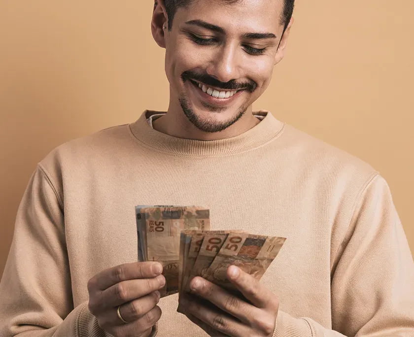 Pix Saque e Pix Troco - foto de um rapaz segurando notas de R$ 50 e sorrindo